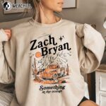 "Zach Bryan merch collection featuring a vintage-inspired T-shirt with album artwork, a cozy hoodie with his logo, and a signed poster."